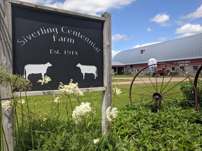 Siverling Centennial Farm road sign with flowers, tractor and barn in background
